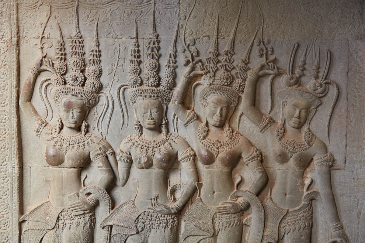 Angkor Wat Celestial Figure Bas-Relief amid raised hands and weathered stone carving in Siem Reap, Cambodia.